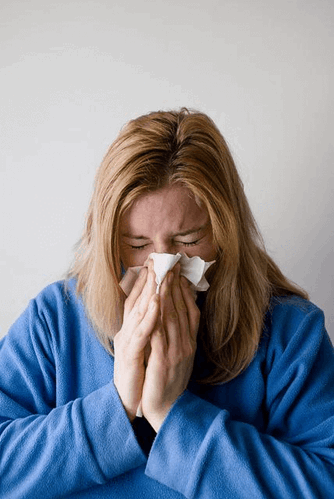 A woman sneezing due to sick leave at work.