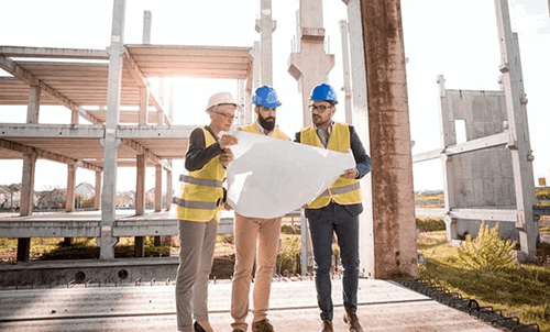 Three construction workers looking at a plan on a piece of paper.