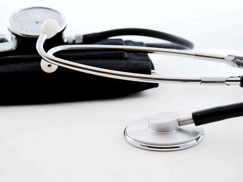 A metal and black stethoscope lying on a table.