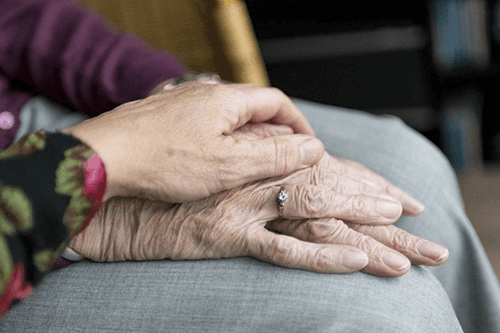 Elderly people holding hands.