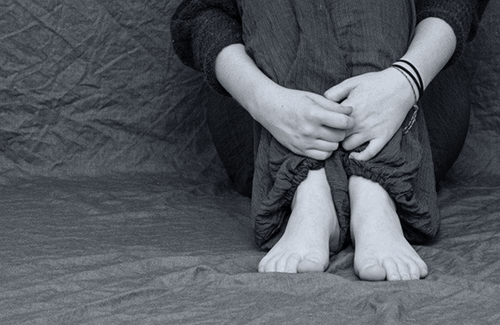 A person holding their legs as they face bullying at work.