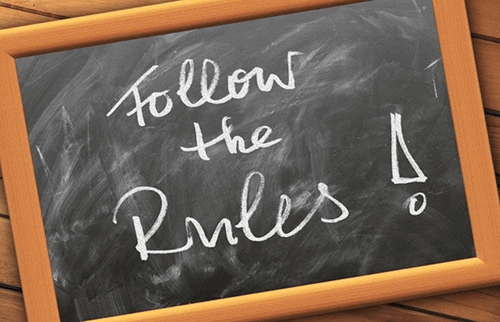 A chalkboard with follow the rules written.