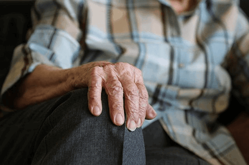 Elderly woman experiencing menopausal symptoms, like body pain.