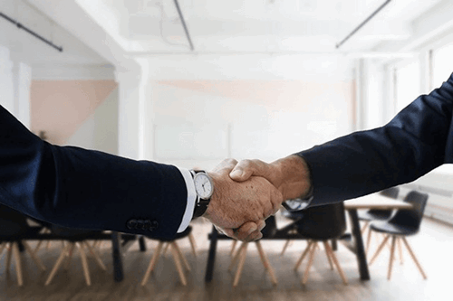 An image of two people shaking hands in a meeting room.
