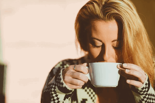 A woman drinking a hot drink on a break from work.