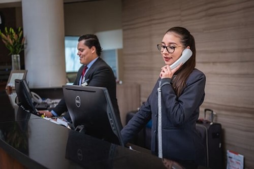 a receptionist using a phone at a hotel front desk